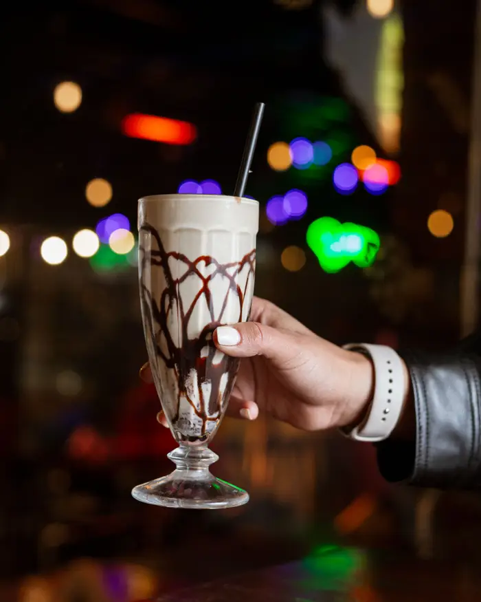 Un Baileys frozen en la mano, con luces de colores detrás
